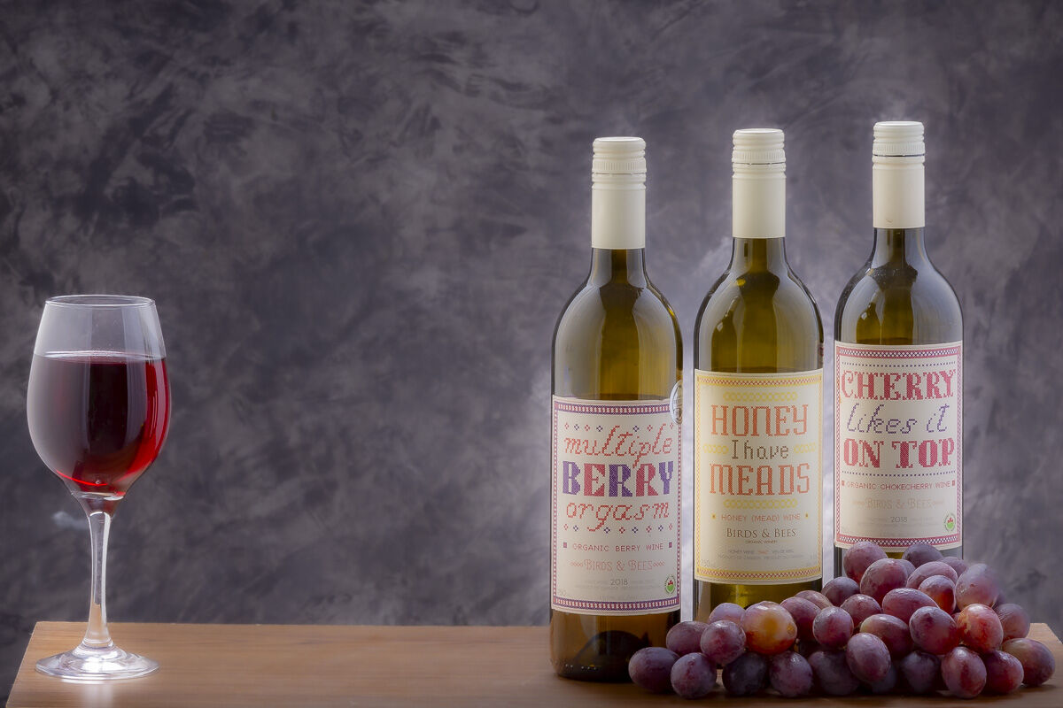 glass of wine with three wine bottles and grapes by David thielen